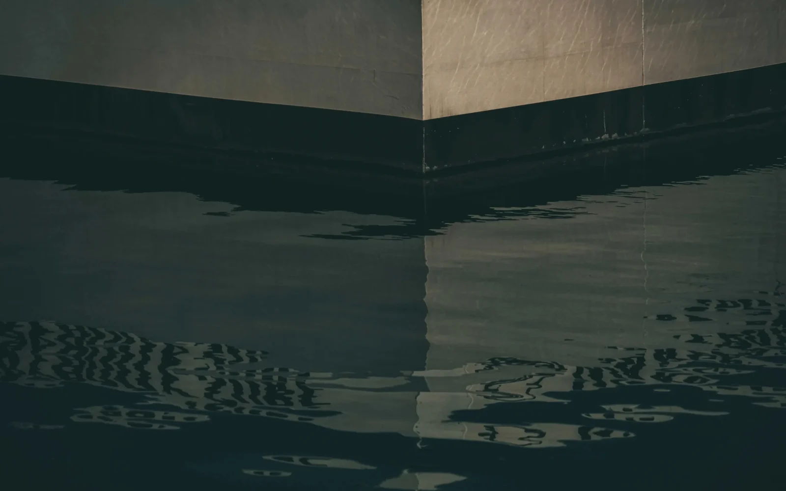 Dark reflective water against again a building, symbolizing the critical infrastructure behind smart water management